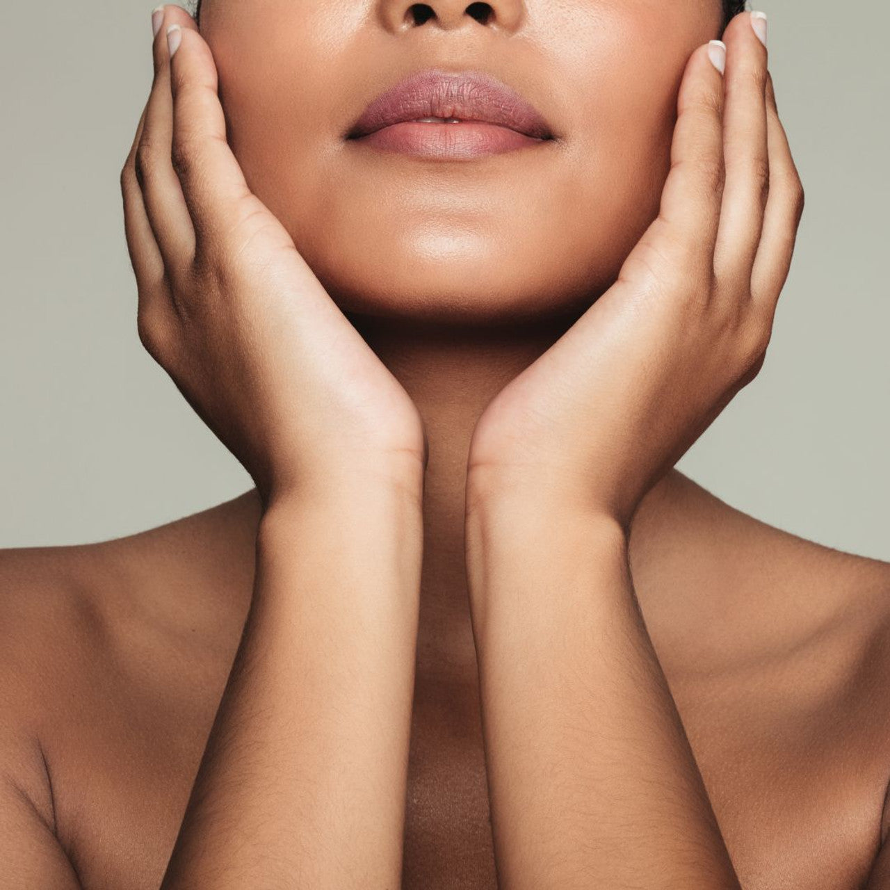 Close-up of a person with hands on face against a neutral background